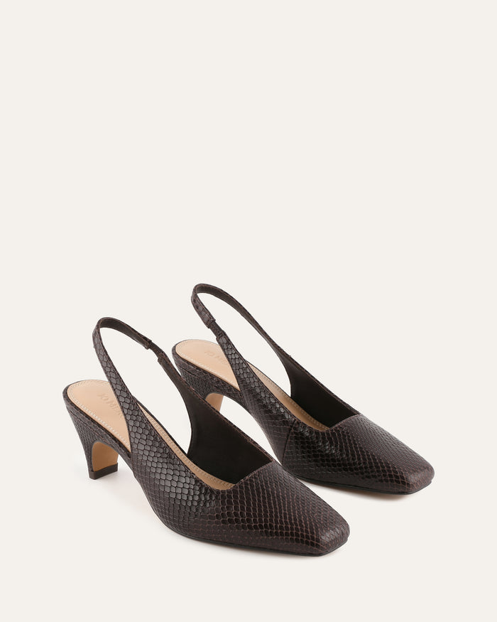 Pair of black slingback heels on a light beige background