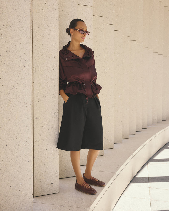 Woman in a stylish outfit standing against a textured wall.