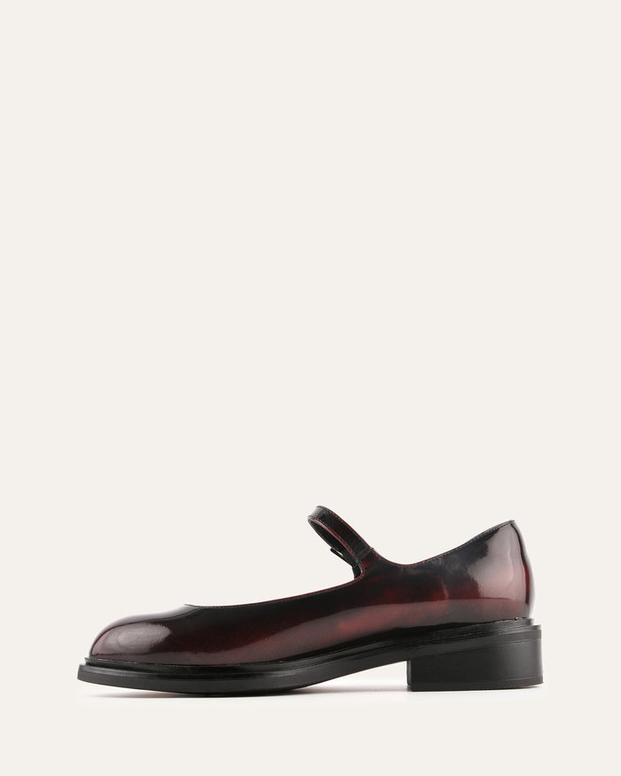 Shiny red shoe with a black sole on a white background