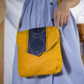 Model carrying handmade hemp crossbody bag with tribal embroidery flap